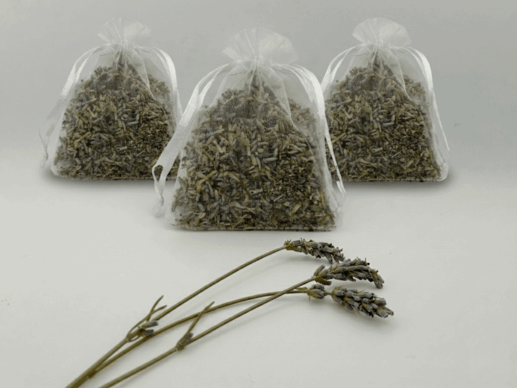 three lavender sachets from moment lavender on white background, which three sprigs of fresh lavender